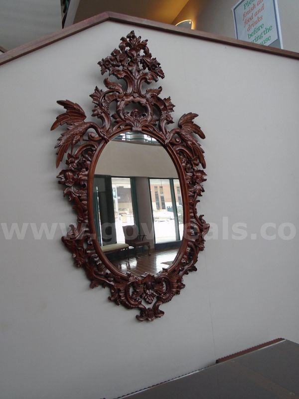 Large carved wood oval wall mirror. Elaborate floral carvings finished in dark mahogany tone