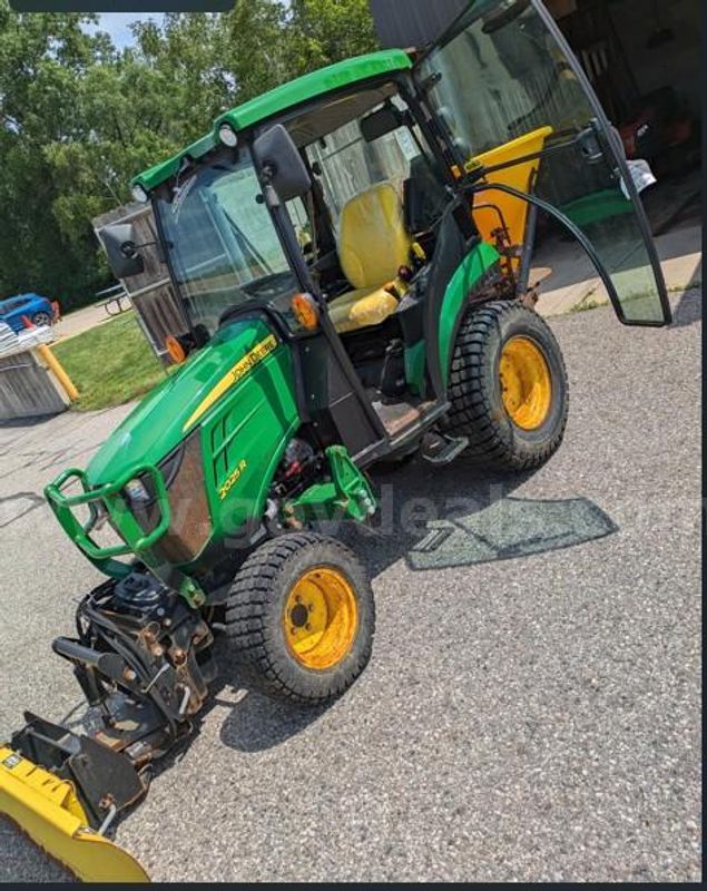 John Deere 2025R Tractor with plow blade and salt spreader